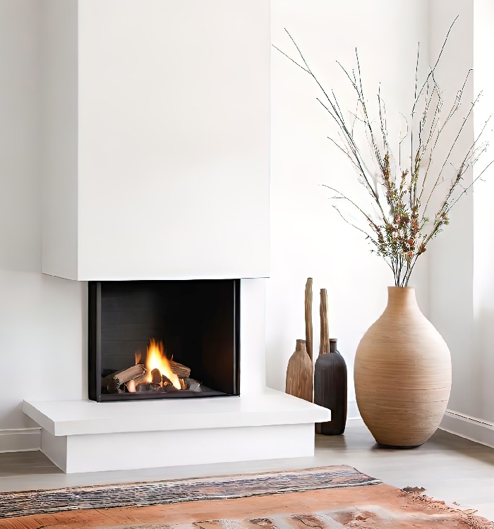 Cheminée contemporaine blanche avec foyer vitré et feu allumé, installation de chauffage au bois avec conduit à entretenir régulièrement